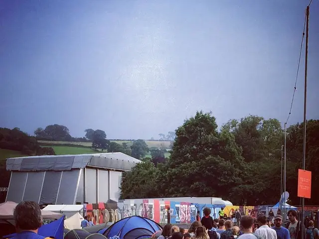 On the ground there are many small tents and beside the tents there is a crowd walking on the...